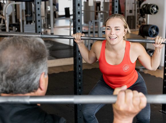 Ledare och medlem tränar med skivstång i gymmet